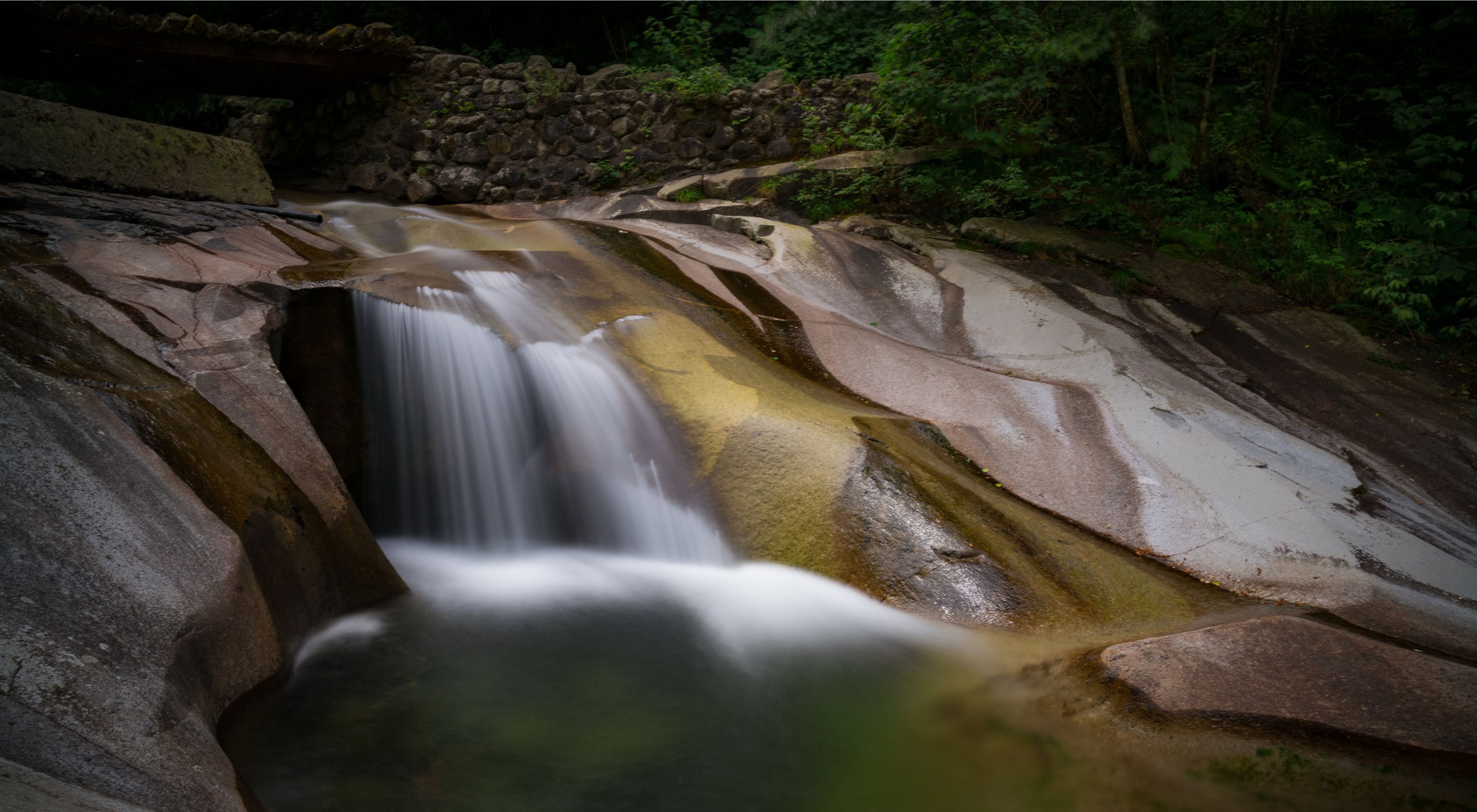 A running stream flows over rocks in Laohegou, Sichuan Province.