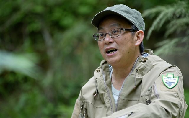 Candid portrait of Liu Xiaogeng in a forest.