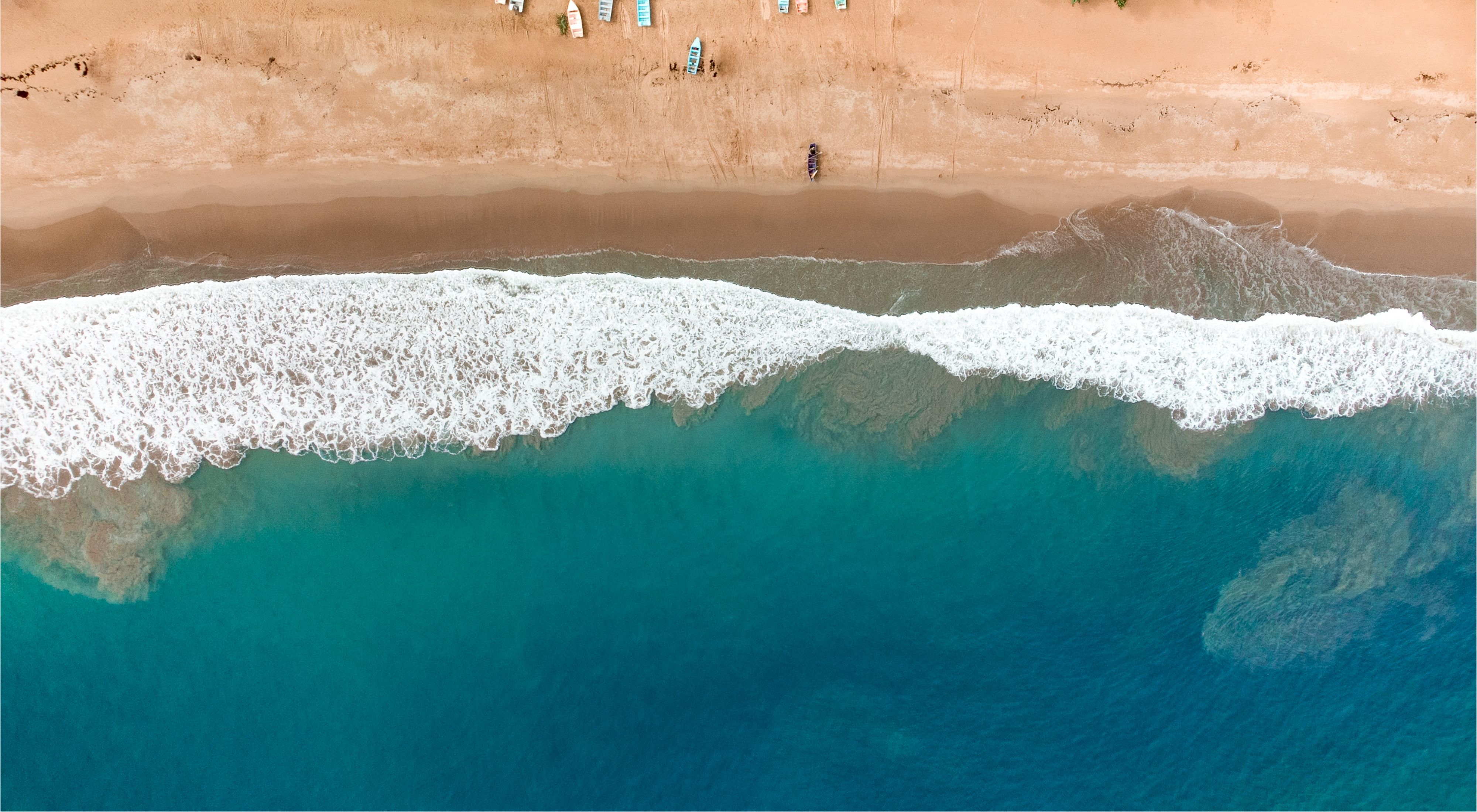 Aerial view of waves lapping against a golden beach in the Dominican Republic.