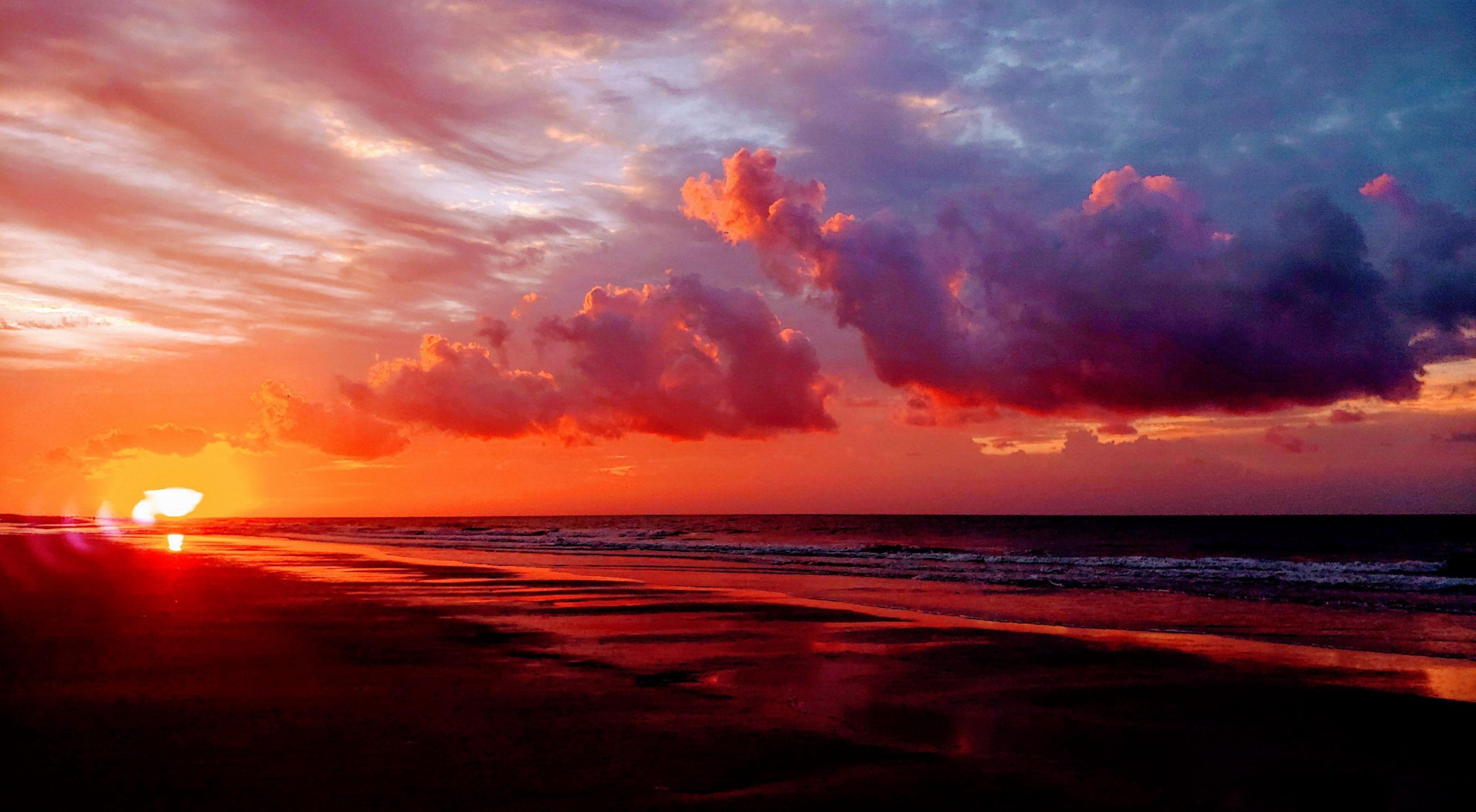 Sunrise over the ocean and a flat sandy beach