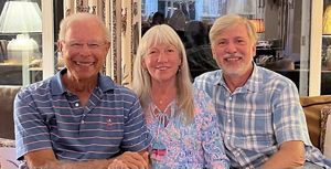 Three people smile for photo.