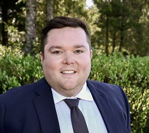 Person standing in suit and smiling.
