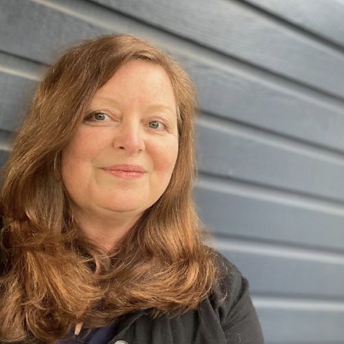 Person smiling in front of a metal wall.