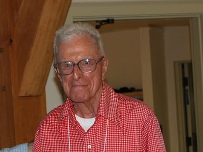 A older man wearing glasses and a red checkered shirt.