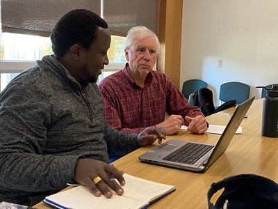 Edwin Njuguna and Dave Courtemanch sit at a table with a laptop.