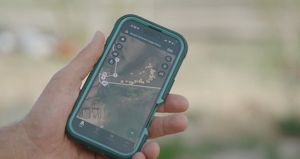 Closeup of an iPhone displaying a map in someone's hand during the daytime.