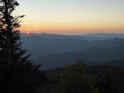 The orange glow of a sun rise lights up a mountain valley.