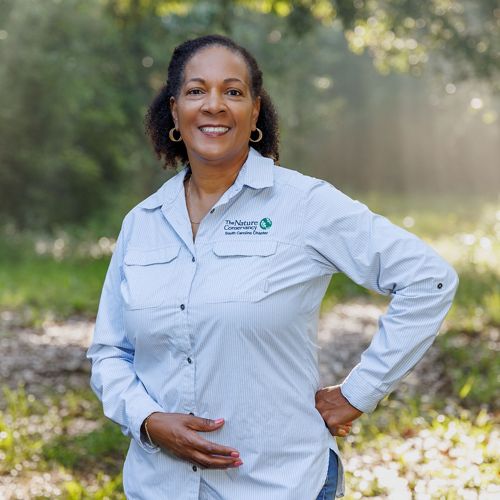 A woman in a blue shirt smiles at the camera.