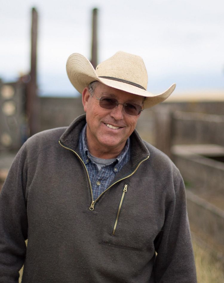 A man wearing a cowboy hat smiles at the camera