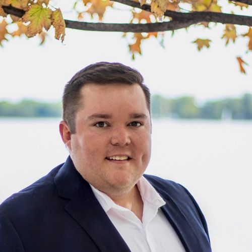 Person standing in suit and smiling.