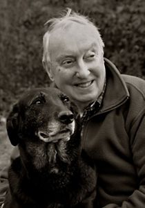 Portrait of a gray-haired white man in a fleece jacket with his dog