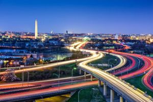 The city skyline of Washington, DC at night showing the lights and the Washington Monument.