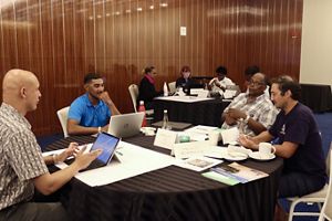 Four people sit and meet around a table. 