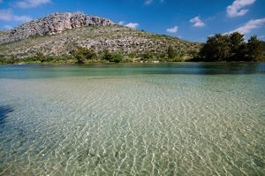 The turquoise waters of a river lined with dense brush ripple and flow.