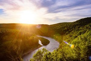 A view of the sun setting over the Delaware River as it meanders between two mountain ranges.