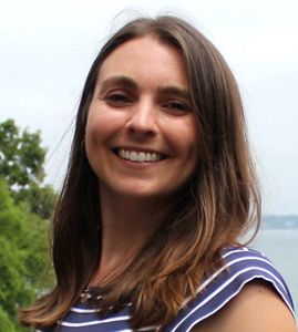 Headshot of Diana Fontaine, a young woman with long brown hair and a navy blue top with the ocean in the background.