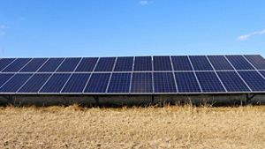Solar panels in a field with blue sky as the backdrop.