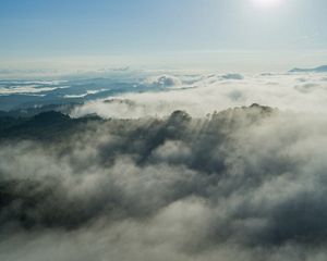 White mist shrouds the peaks of mountain ridges and fills the deep valleys.