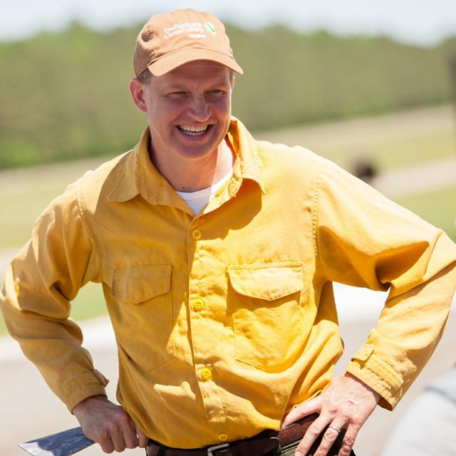 Candid photo of a smiling man wearing a yellow shirt.