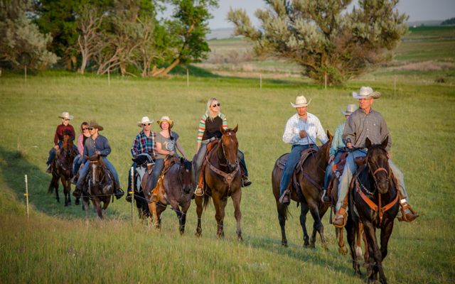 The Doan Family (ten people) on horses riding through a pasture.