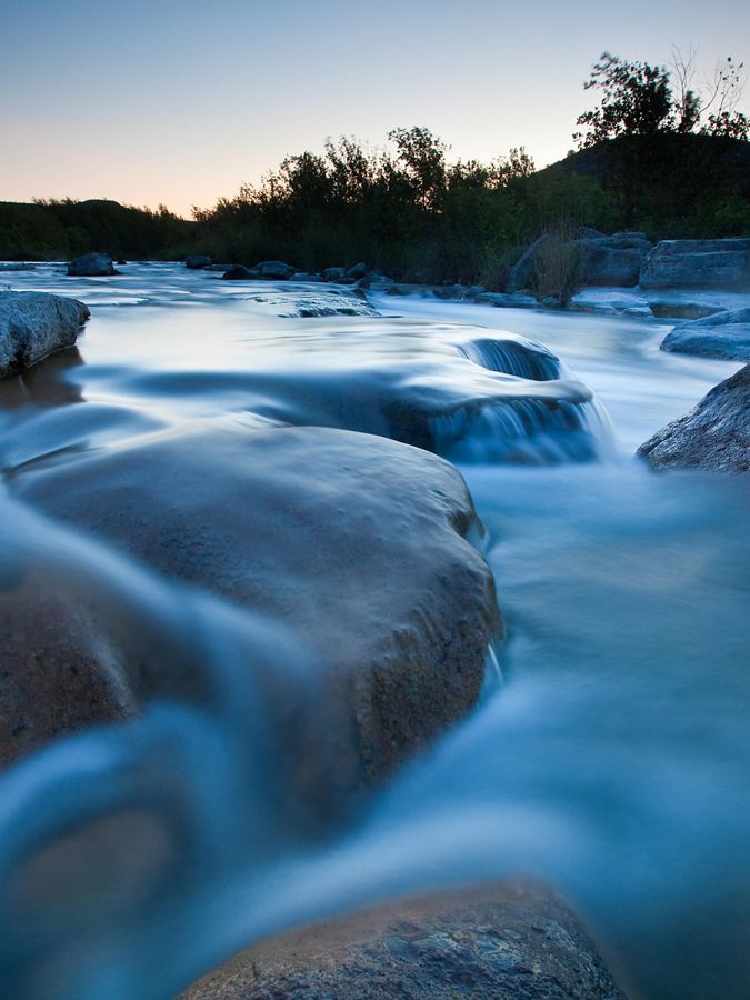 Blue waters flow over large stone boulders.