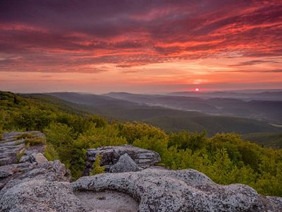 Rocky outcrop of the sun on the horizon lighting up the sky in pinks and oranges.