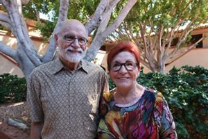 A couple standing in front of their house.