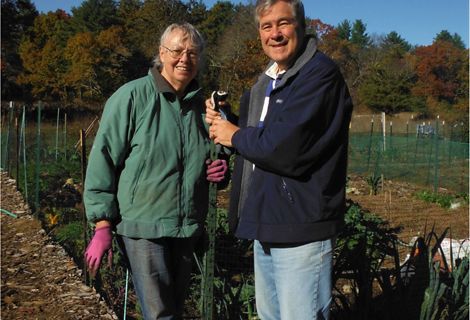 Betty and Neal Sanders stand outside in a garden and smile for the camera.