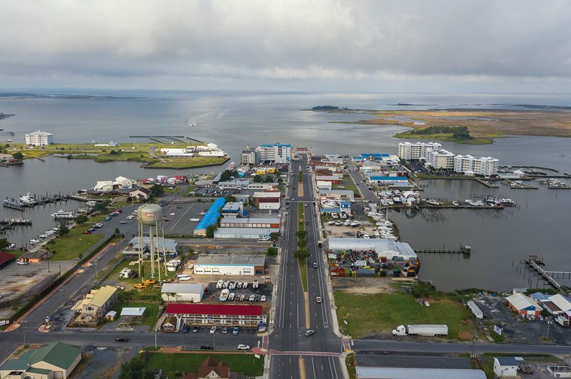 Aerial view of the coastal community of Crisfield, MD. A paved main street runs through the center of the town, dead ending at the water that surrounds the community on three sides.  