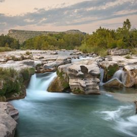 Turquoise water rushes over large boulders, creating a tumbling waterfall.