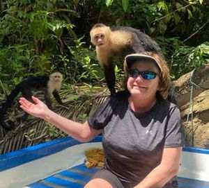 A woman with a monkey on her shoulder poses for a picture.