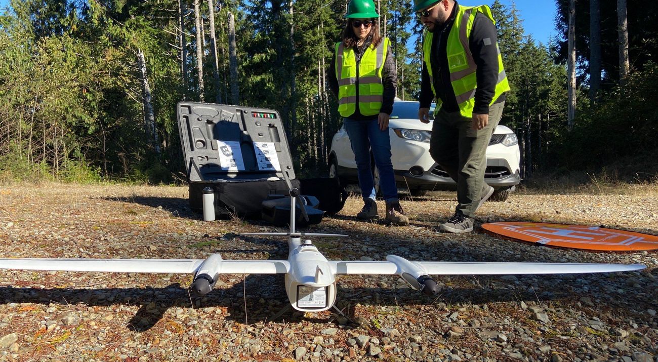 a large drone on the ground with two people standing behind it.