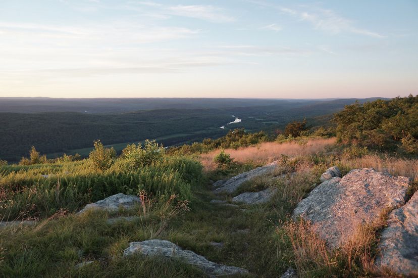 Green forested mountain ridges and valley stretch out to the horizon as the sun rises on the Appalachian Trail.