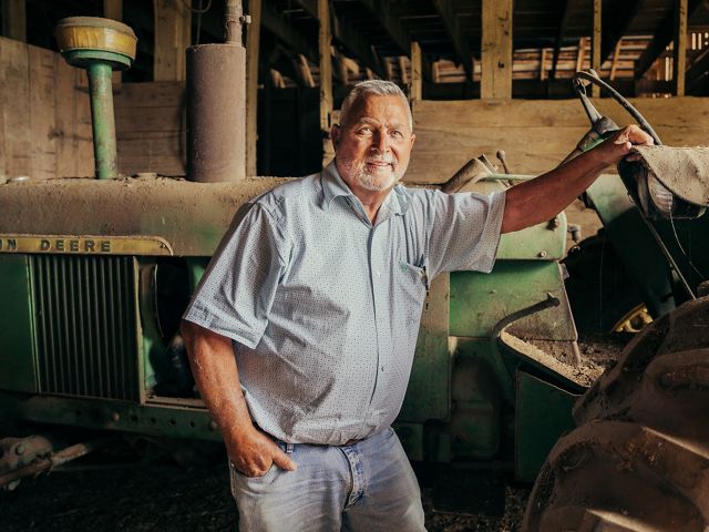 Grant Victor poses with a tractor on his ranch in Akton, Oklahoma