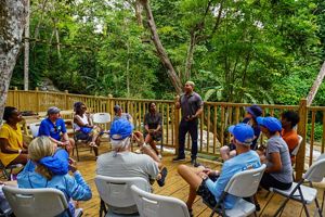 Two Jamaicans give a presentation in the jungle to a group of people.