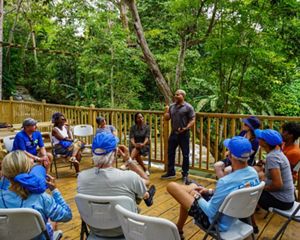 A group of people gather for a presentation in front of a river.