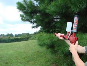 A hand held device containing incendiary spheres is pointed at an open meadow in a demostration of its use in a controlled burn.