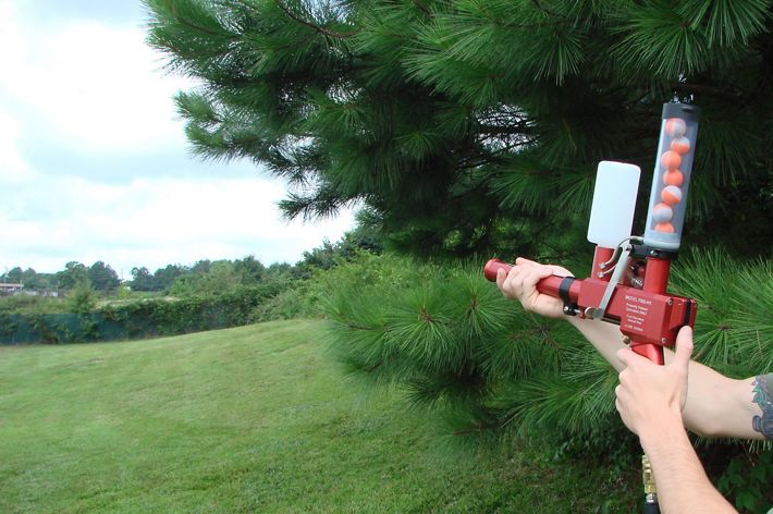 A hand held device containing incendiary spheres is pointed at an open meadow in a demostration of its use in a controlled burn.