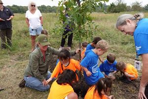 A group of children plants a tree with help from The Nature Conservancy staff.
