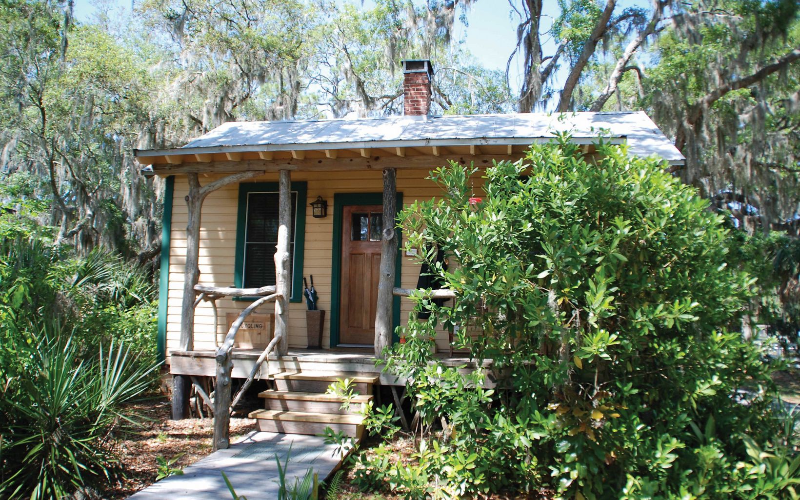 A small cabin accommodation on Little St. Simons Island nestles amongst green grasses and trees draped in spanish moss.