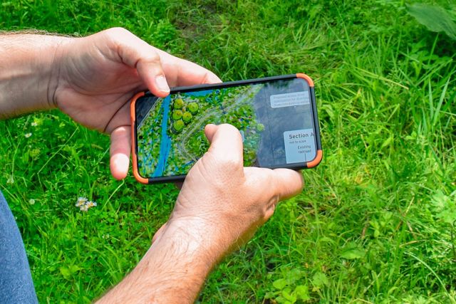 A close up of a person's hands holding a phone showing a map.