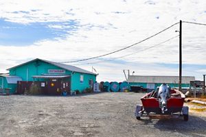 A small wooden building with a sign that reads "restaurant" sits in a gravel lot. 