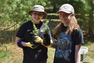 Two young people helping plant trees.
