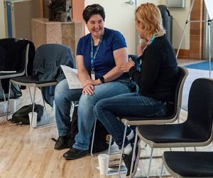 Two people sitting in chairs talking and laughing.