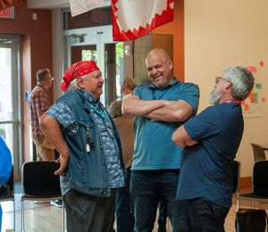 Three men stand together and laugh.