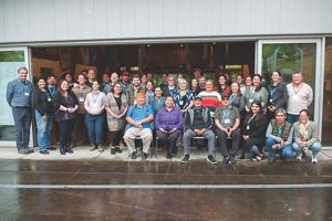 A large group of people gather for a group photo in front of a building.