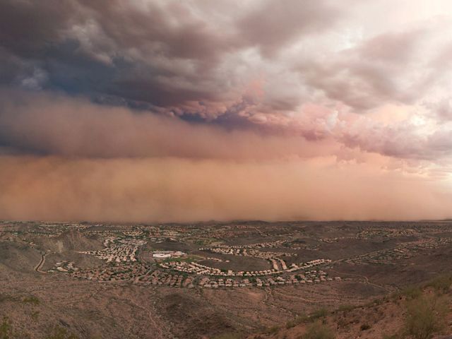 Gray and pink dust clouds over buildings in the distance near Phoenix, Arizona.