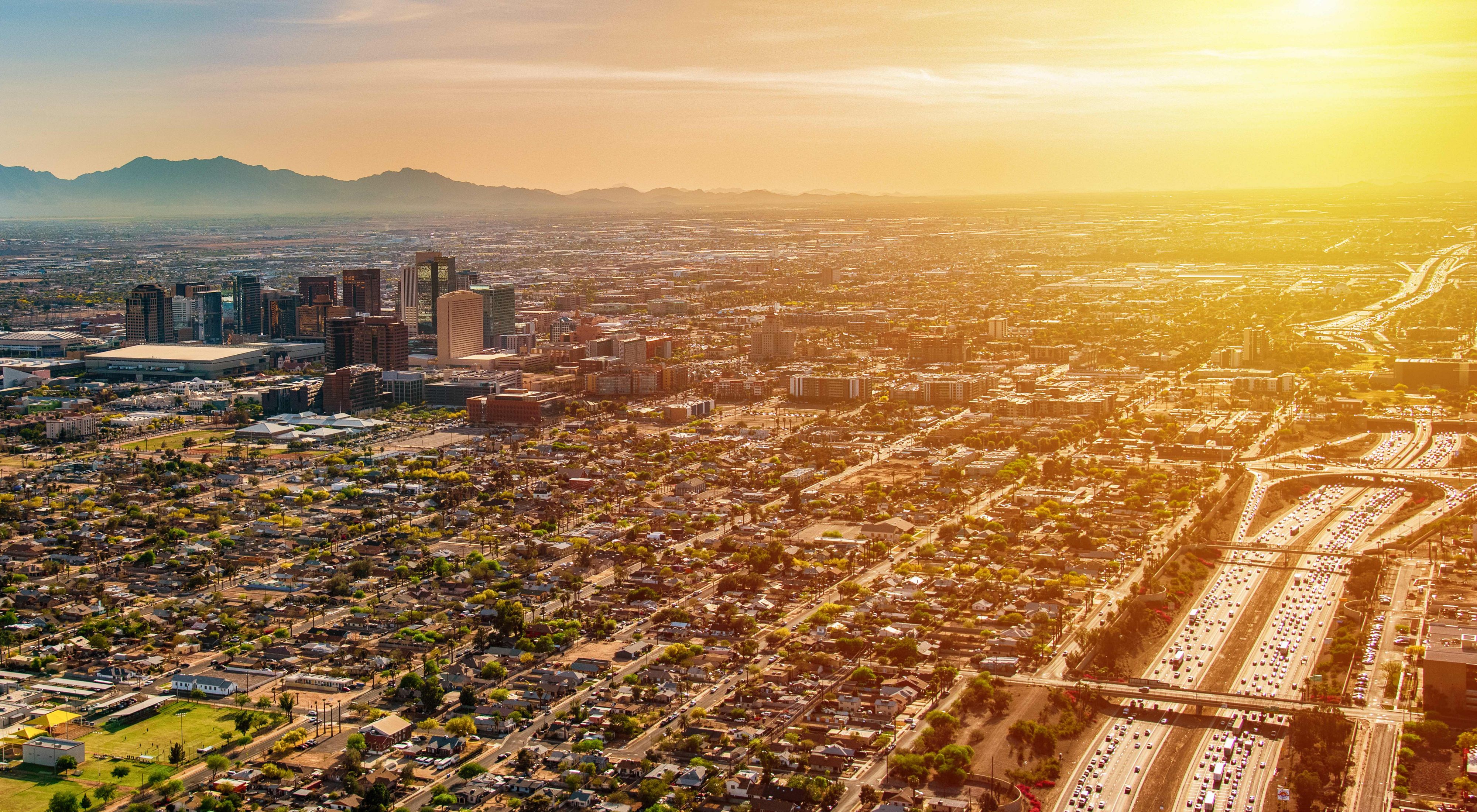 An aerial view of downtown Phoenix, Arizona and the surrounding urban area from an altitude of about 2,000 feet over the desert floor during dusk.