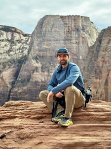 A man siting on a rock smiling at the camera.