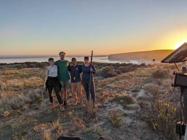 Four people stand together on a bluff overlooking the ocean at Dangermond Preserve in California.